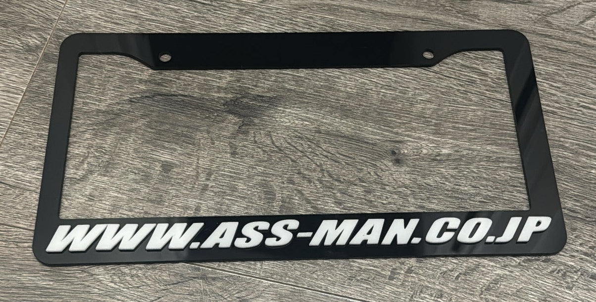 Black license plate frame with URL on a wooden surface